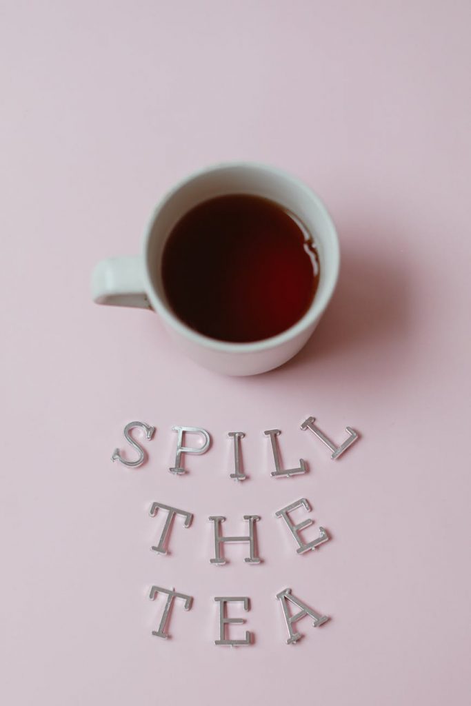 a cup of tea beside the silver letters on a pink surface